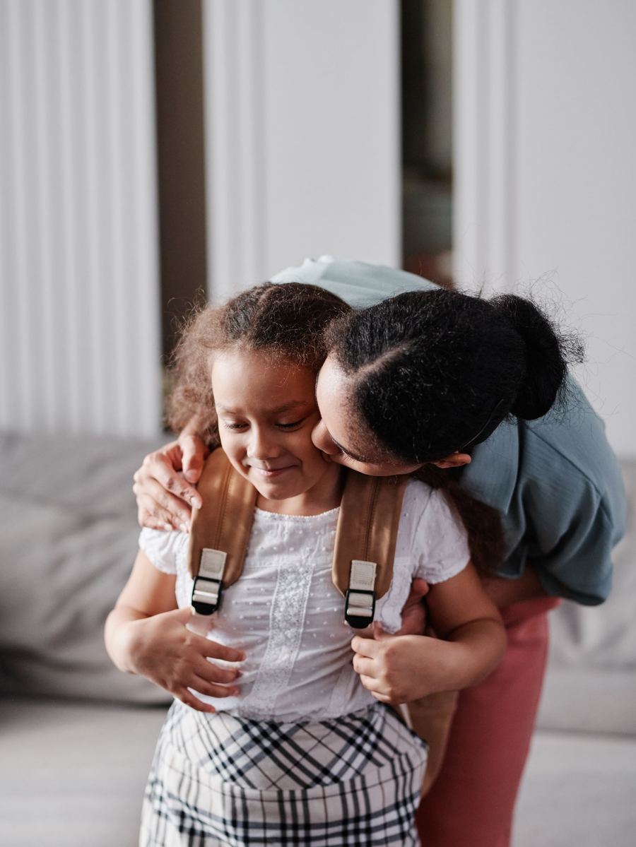 Mamá abrazando a su hija con mochila antes de ir a la escuela